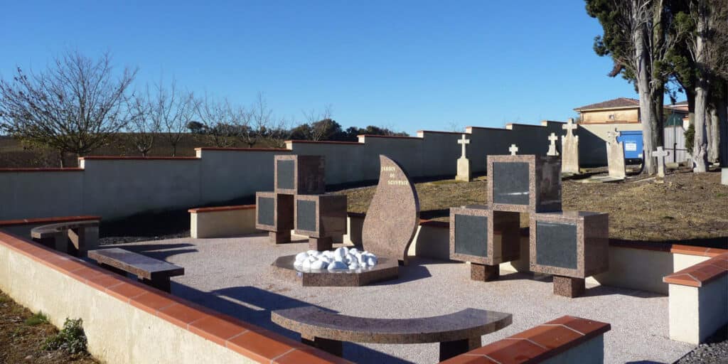 Jardin du Souvenir : Espace cinéraire moderne et columbariums Jardin du Souvenir au cimetière avec monument central 'JARDIN DU SOUVENIR', columbariums en granit, bancs, et sépultures.