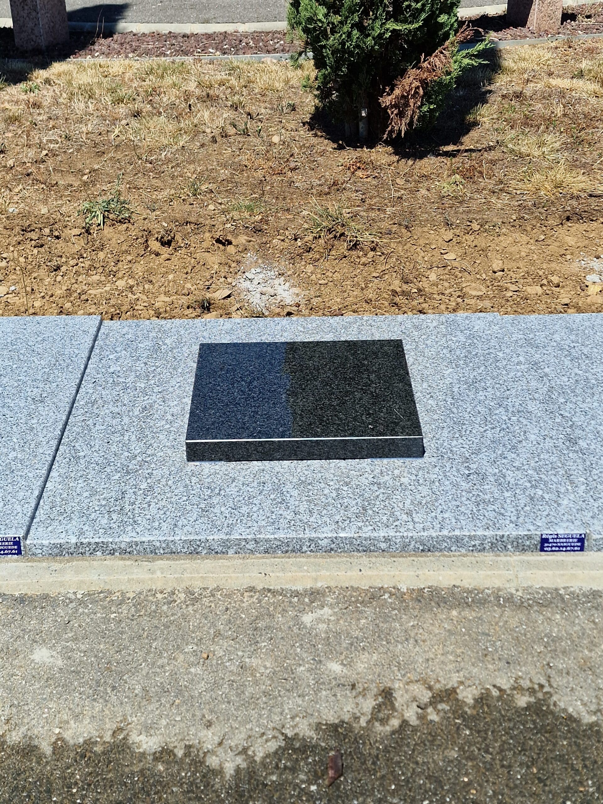 Plaque funéraire en granit noir poli sur socle gris par la Marbrerie Régis Seguela, installation dans un cimetière.