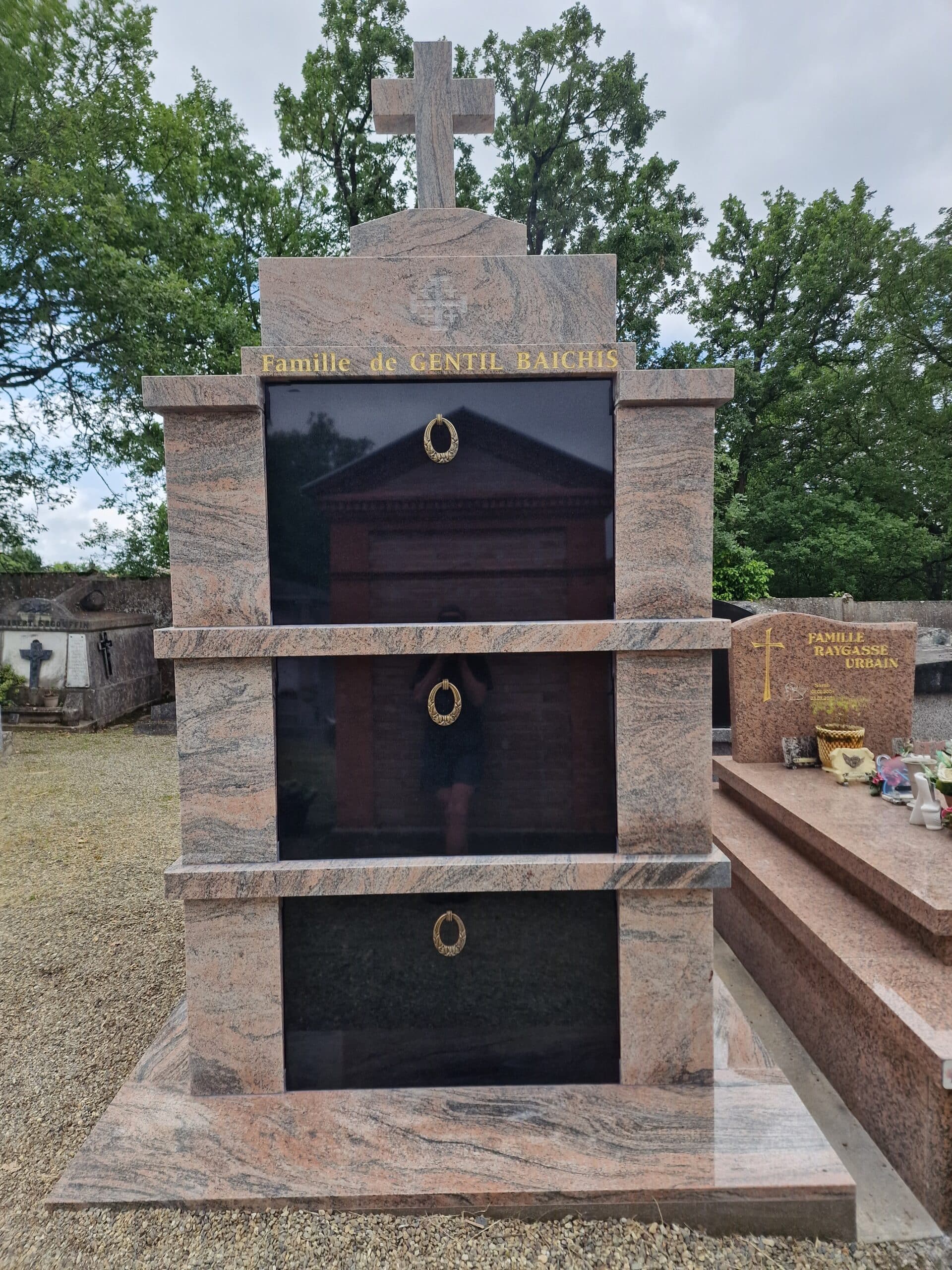 Monument funéraire en granit rose Famille de Gentil Baichis avec trois plaques noires et une croix en pierre au cimetière.