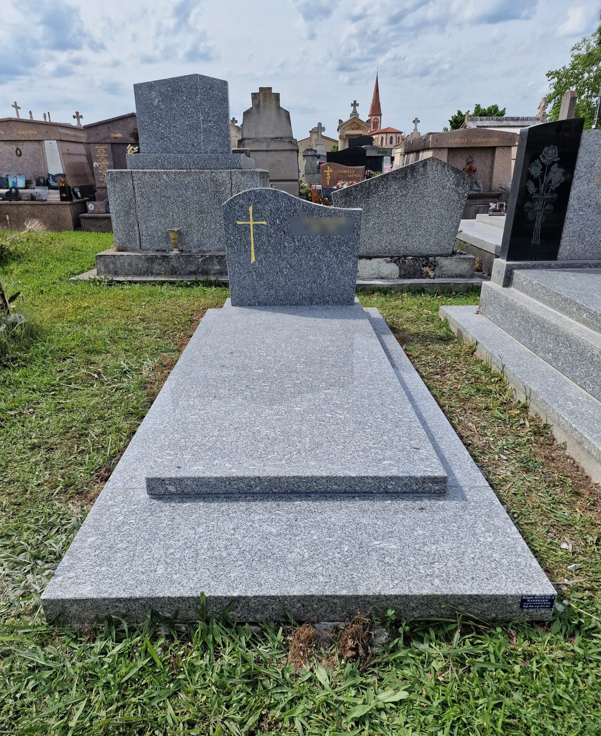 Monument funéraire en granit gris avec croix dorée au cimetière, par la Marbrerie Régis Séguéla à Saiguède.