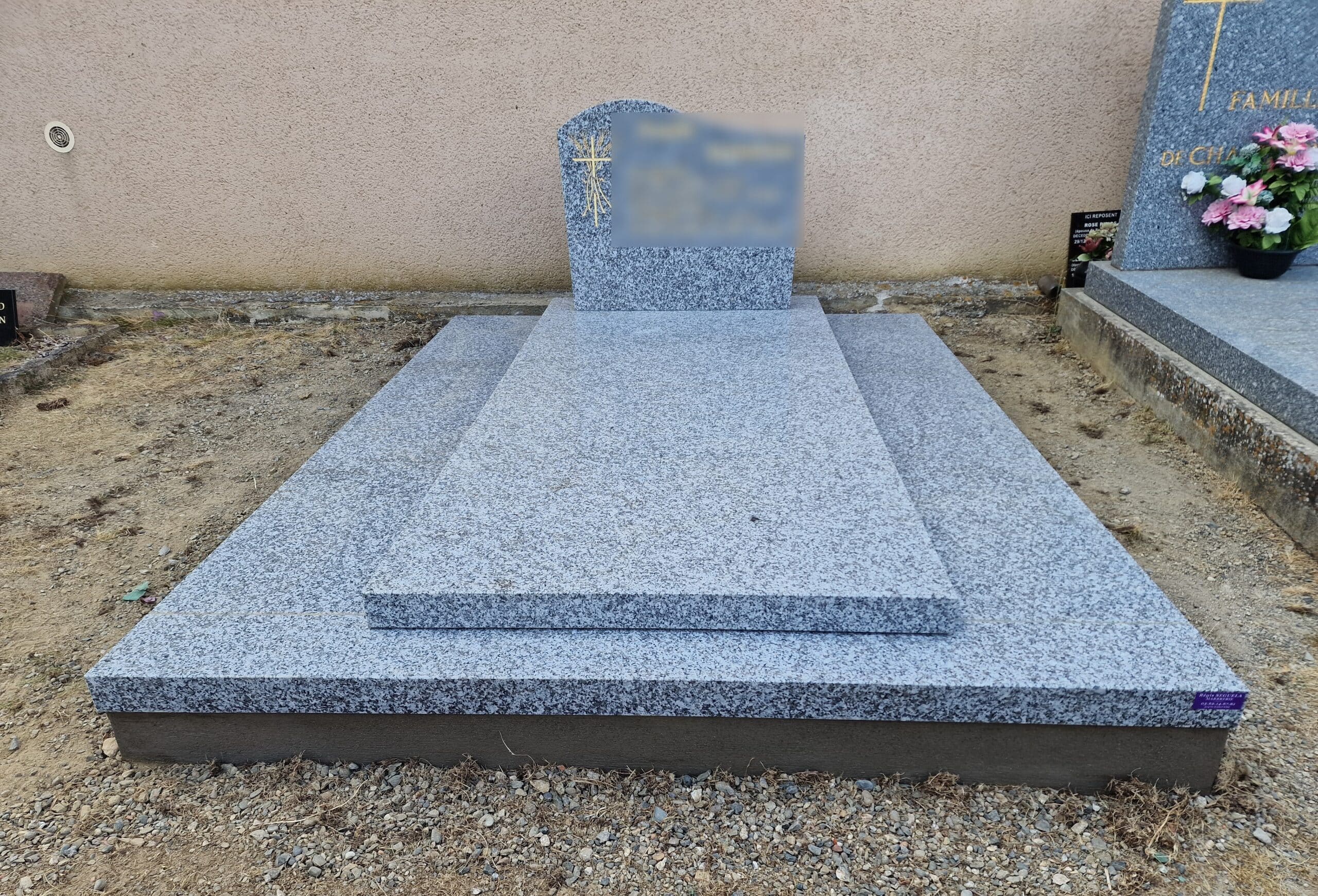 Monument funéraire en granit gris poli avec stèle gravée d'une croix et soubassement à deux niveaux.