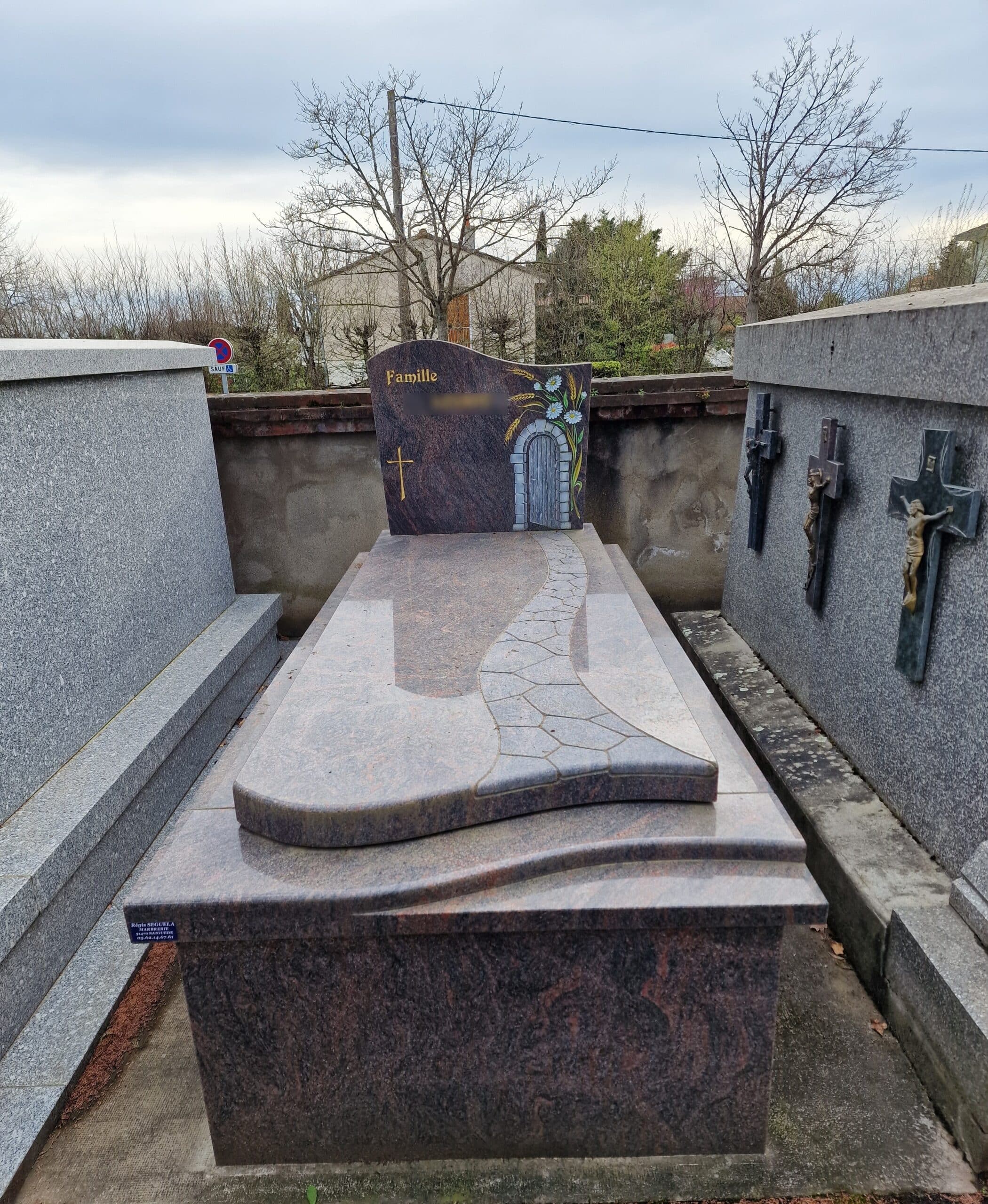 Monument funéraire en granit poli avec décor de porte fleurie et gravure Famille par la marbrerie Régis Seguela.