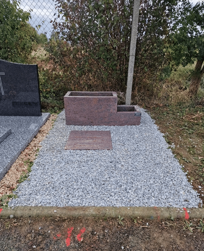 Monument funéraire en granit rose avec jardinière intégrée, plaque au sol et gravillons gris dans un cimetière.