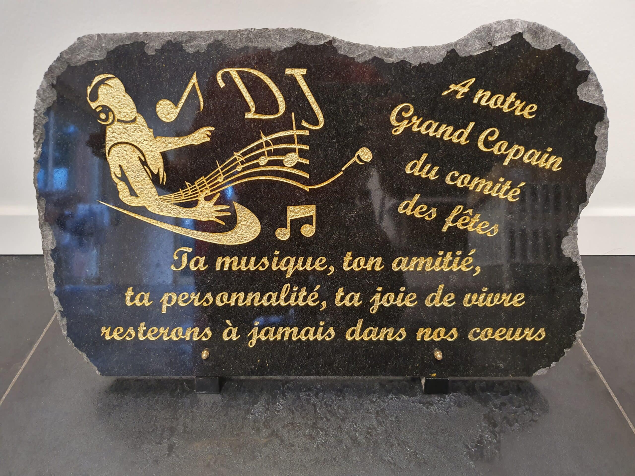 Plaque commémorative en granit noir pour un DJ avec gravures dorées et message d'amitié du comité des fêtes.
