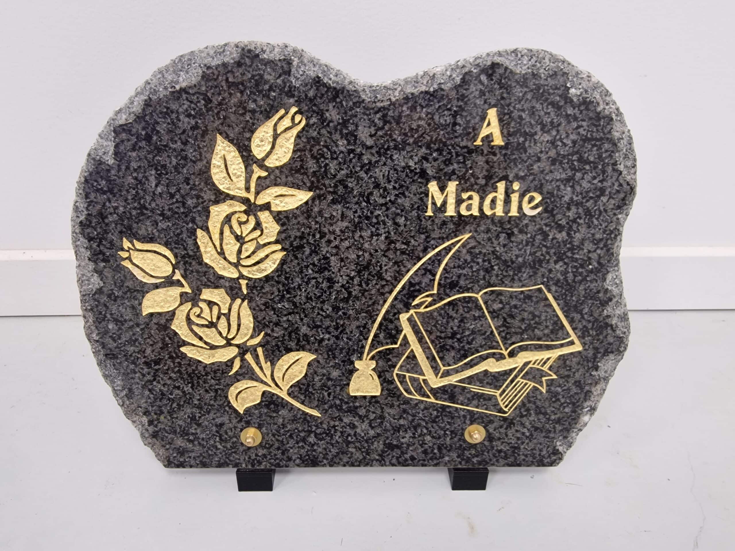 Plaque funéraire cœur en granit gris, gravures dorées de roses, livre, plume et inscription "A Madie".