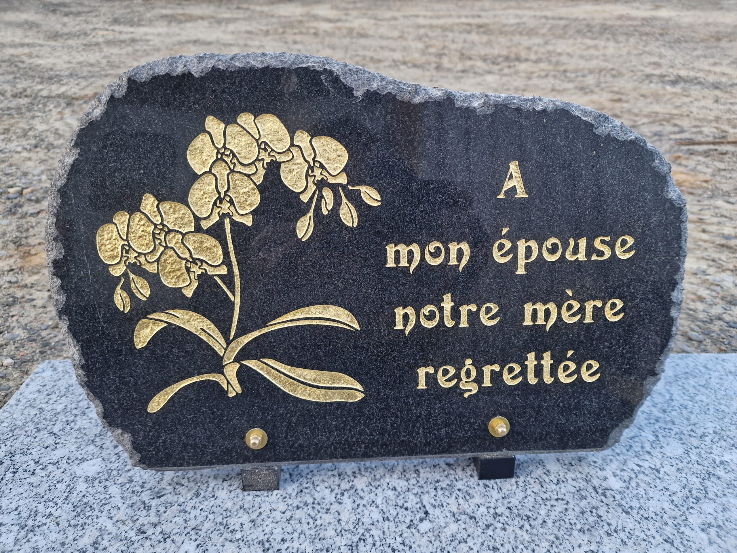Plaque funéraire en granit avec orchidée dorée et message 'A mon épouse notre mère regrettée' pour un dernier hommage.