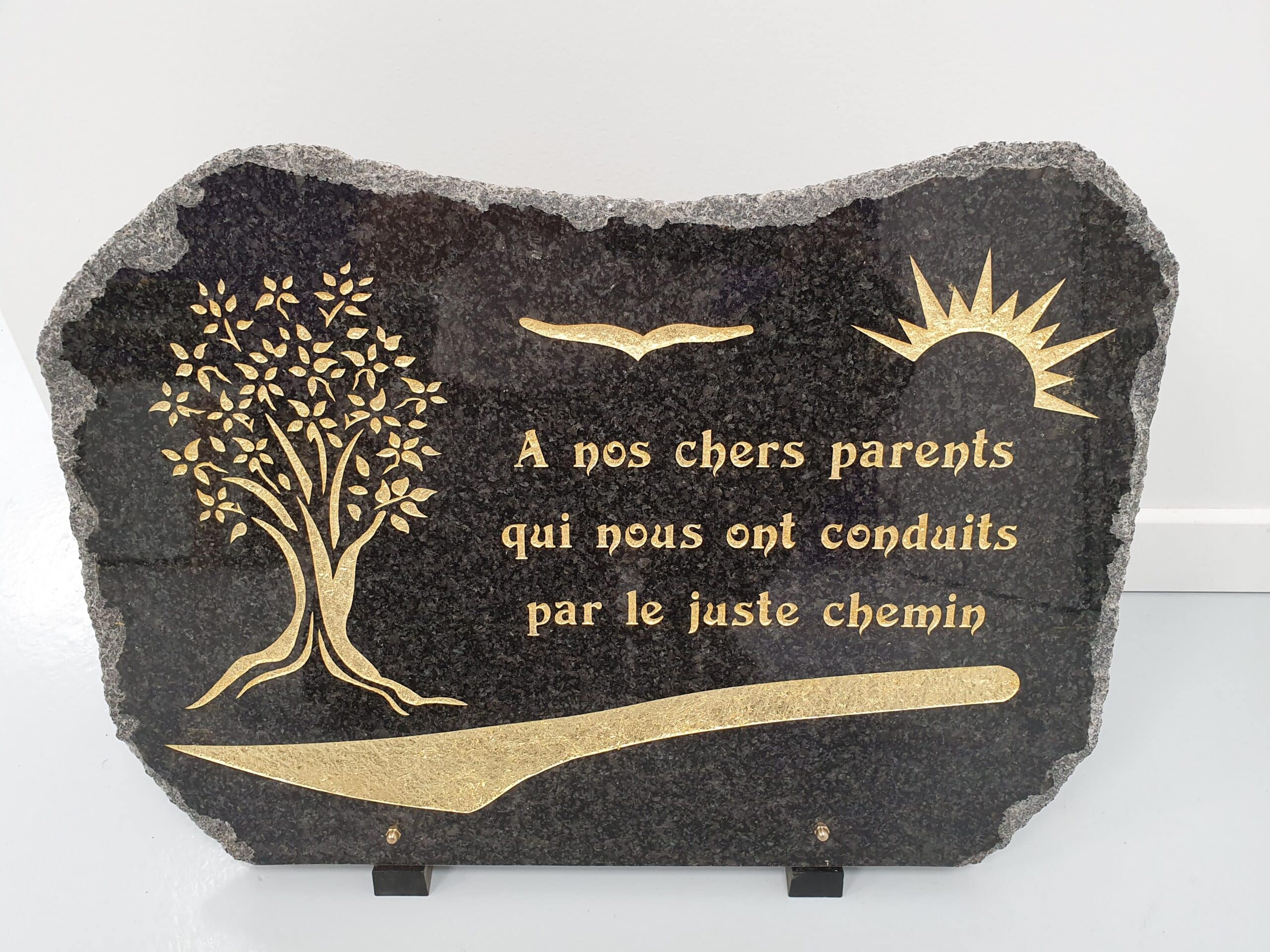 Plaque funéraire granit : "A nos chers parents qui nous ont conduits par le juste chemin", motifs arbre et soleil dorés.