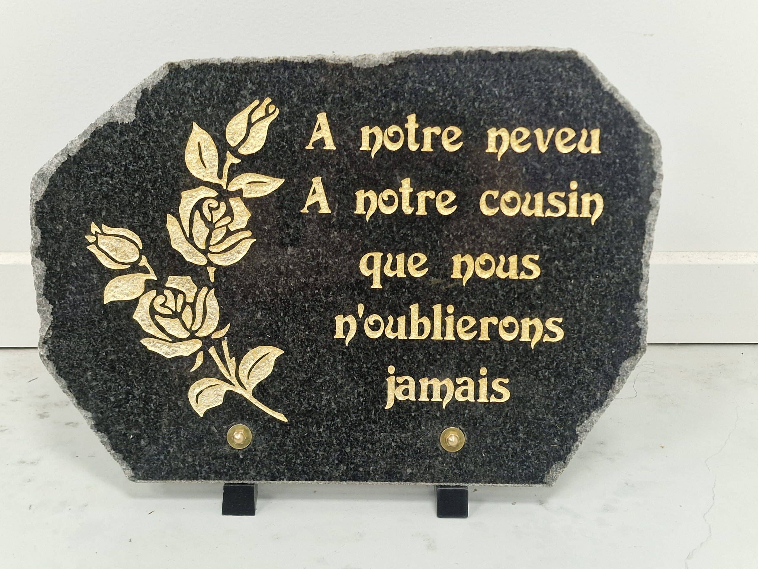 Plaque funéraire en granit noir avec roses dorées : 'A notre neveu, A notre cousin que nous n'oublierons jamais'.