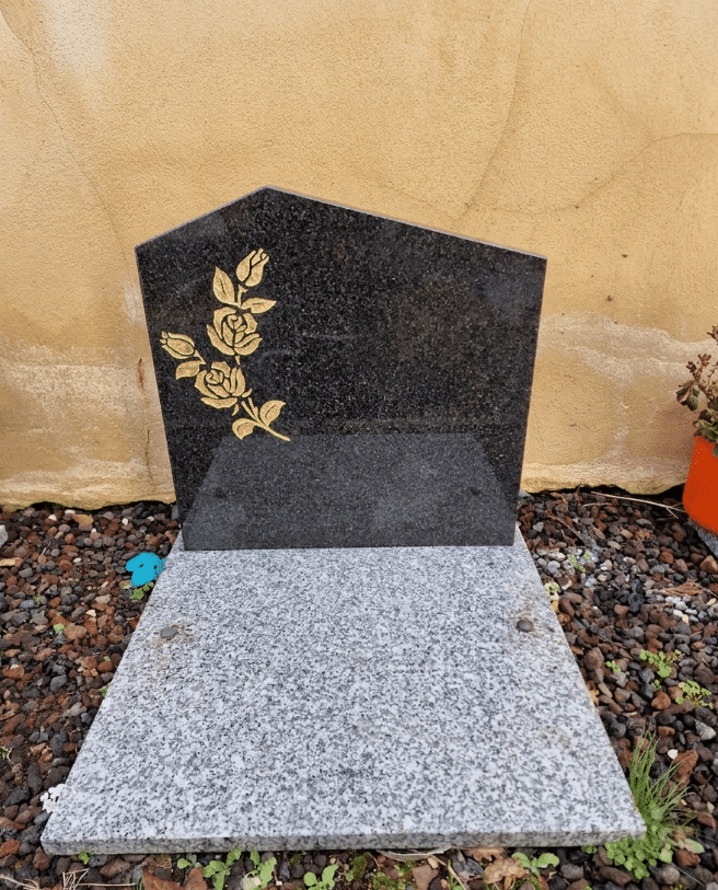 Monument funéraire en granit noir asymétrique avec gravure de roses dorées sur socle en granit gris.