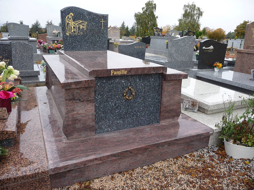 Tombe en granit rouge et gris poli dans un cimetière. Stèle gravée d'un artisan, croix et inscription 'Famille' avec couronne dorée.